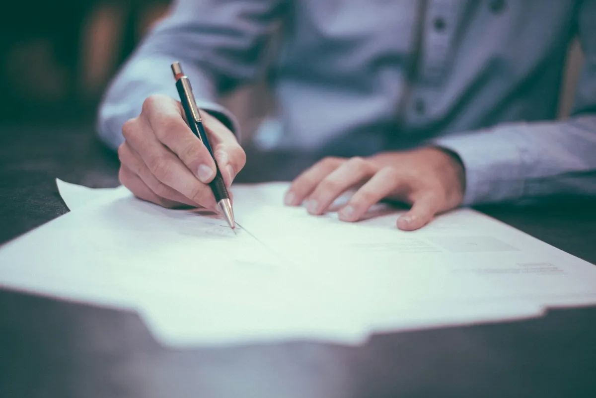 A person signing a rental contract with a pen