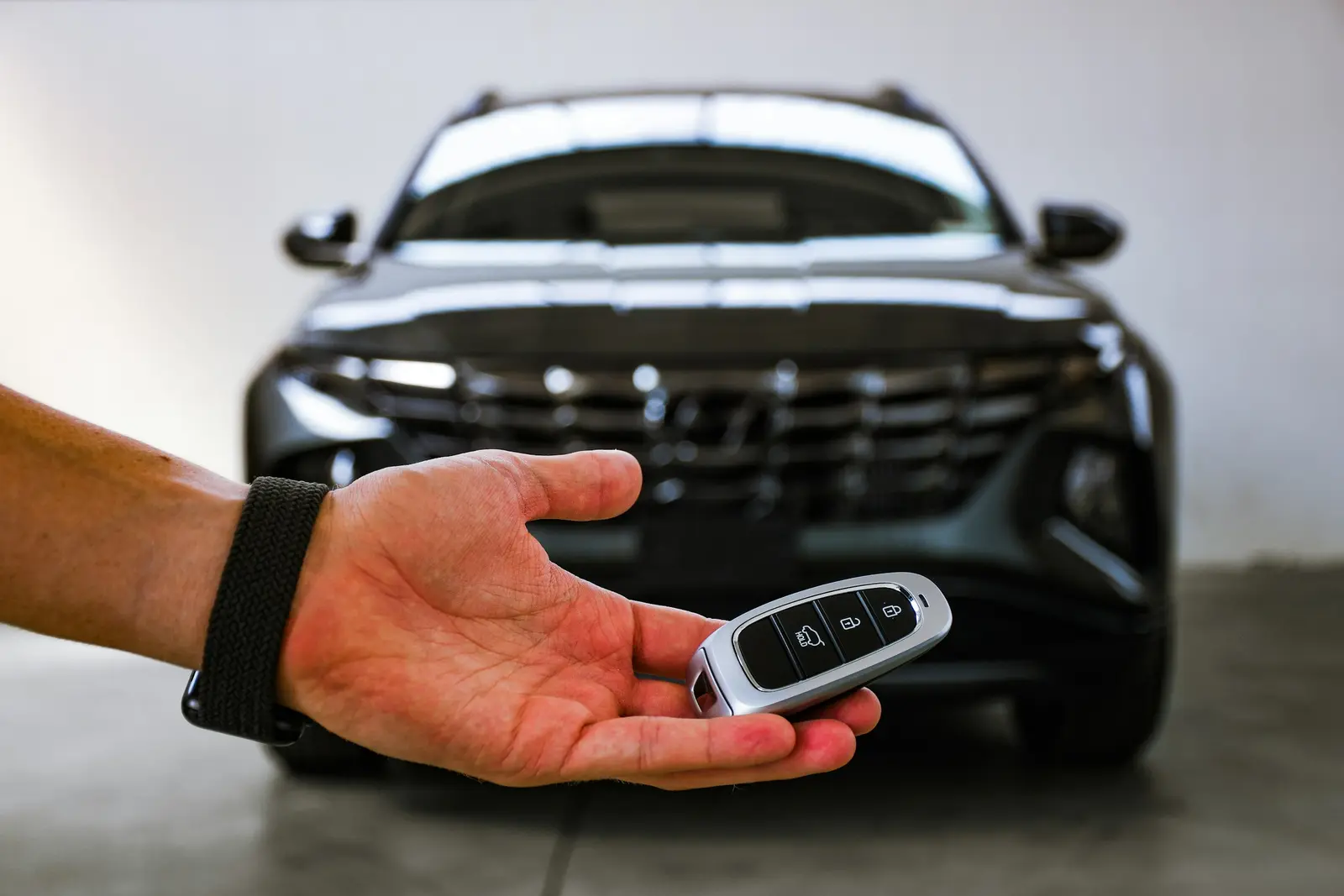 A rental car key handed over in front of a Hyundai SUV, the point where the mandatory Tarifa Basica insurance is added to the total