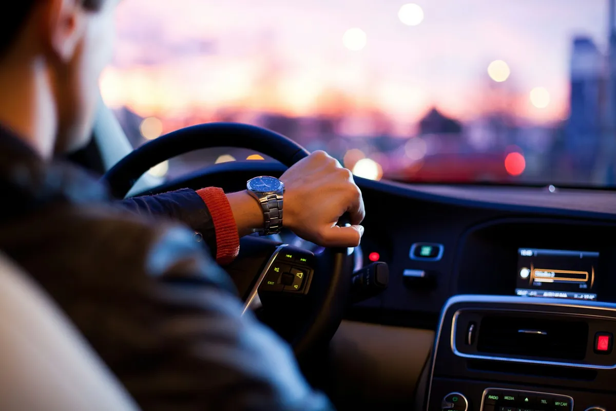 A driver's hand on the wheel of a rental car at dusk in Costa Rica