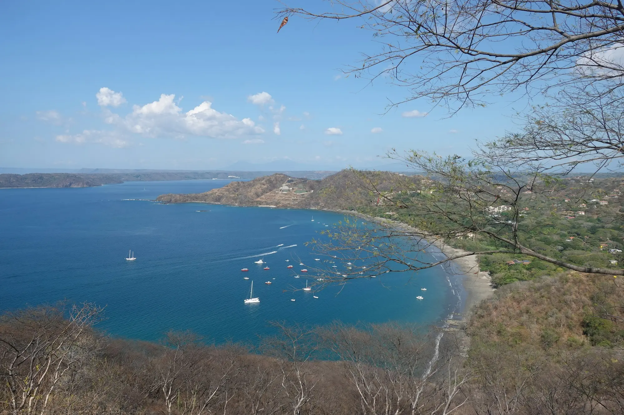 Aerial view of the calm Gulf of Papagayo with sailboats anchored below a resort hillside in Guanacaste, Costa Rica