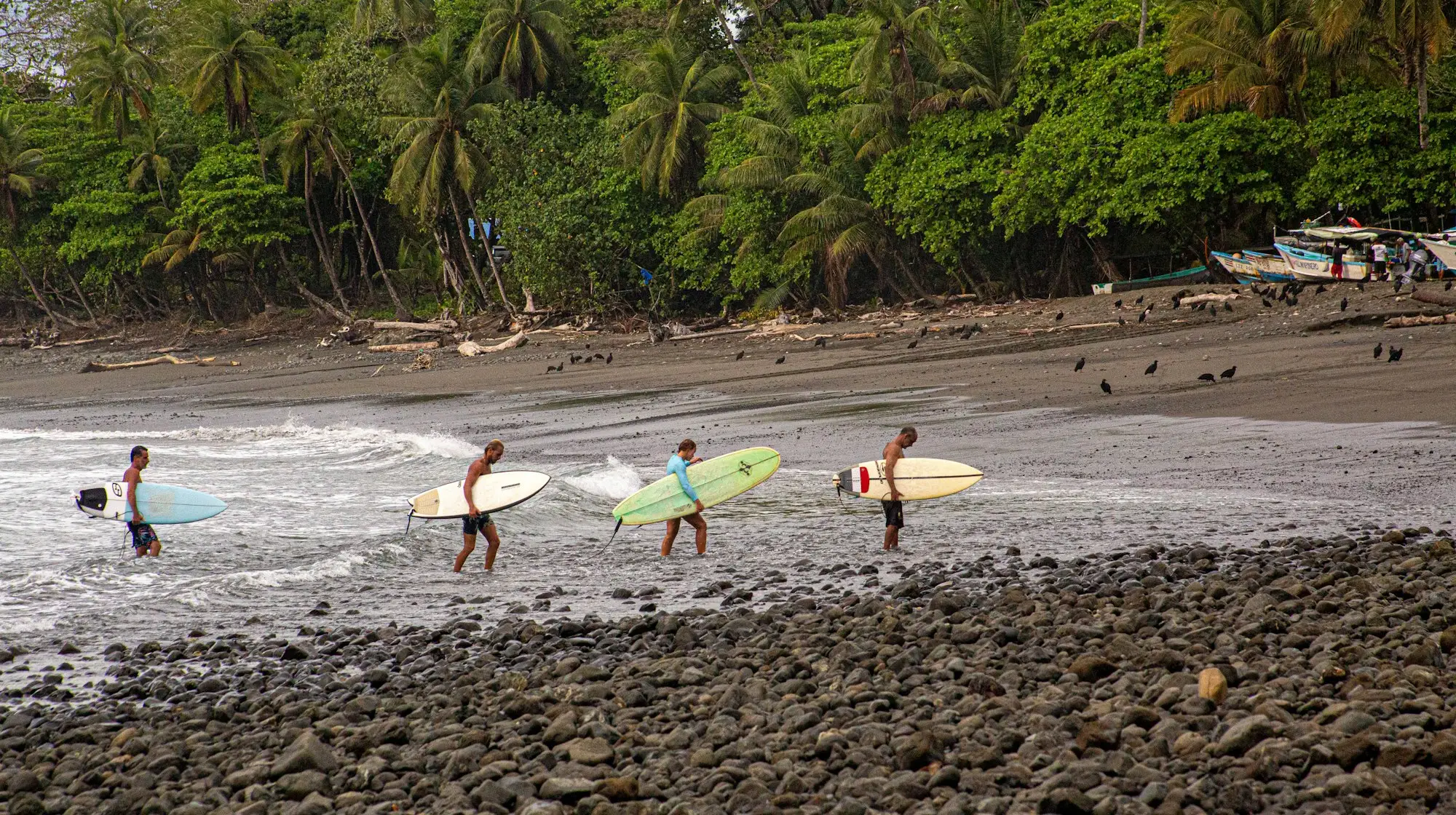 Surfers carrying their boards along a Pacific beach near Tamarindo, Costa Rica