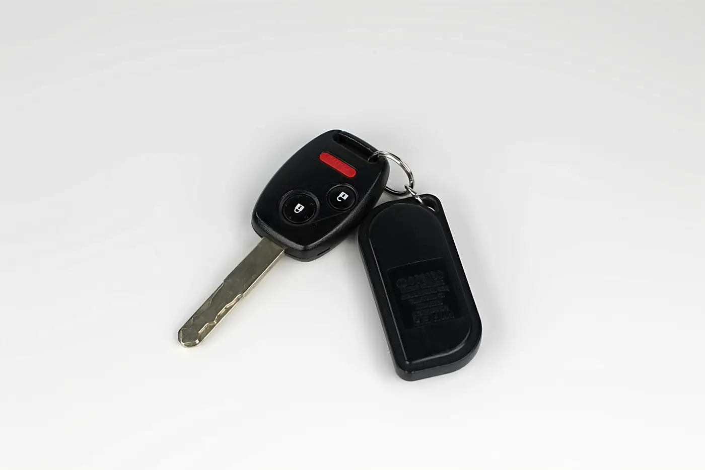 A car key and remote fob resting on a plain white surface