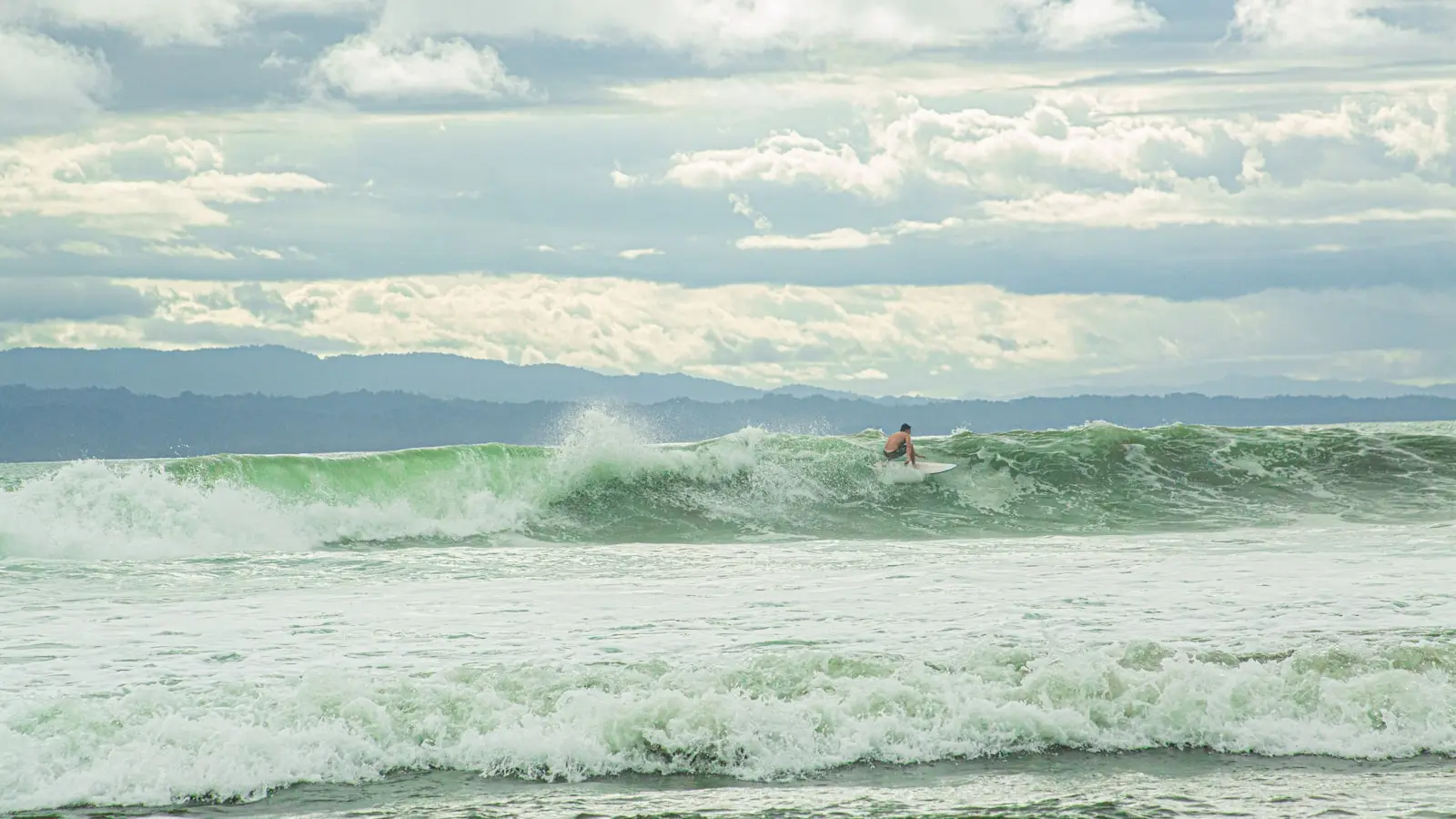 A surfer riding a green wave off the Costa Rican Pacific coast